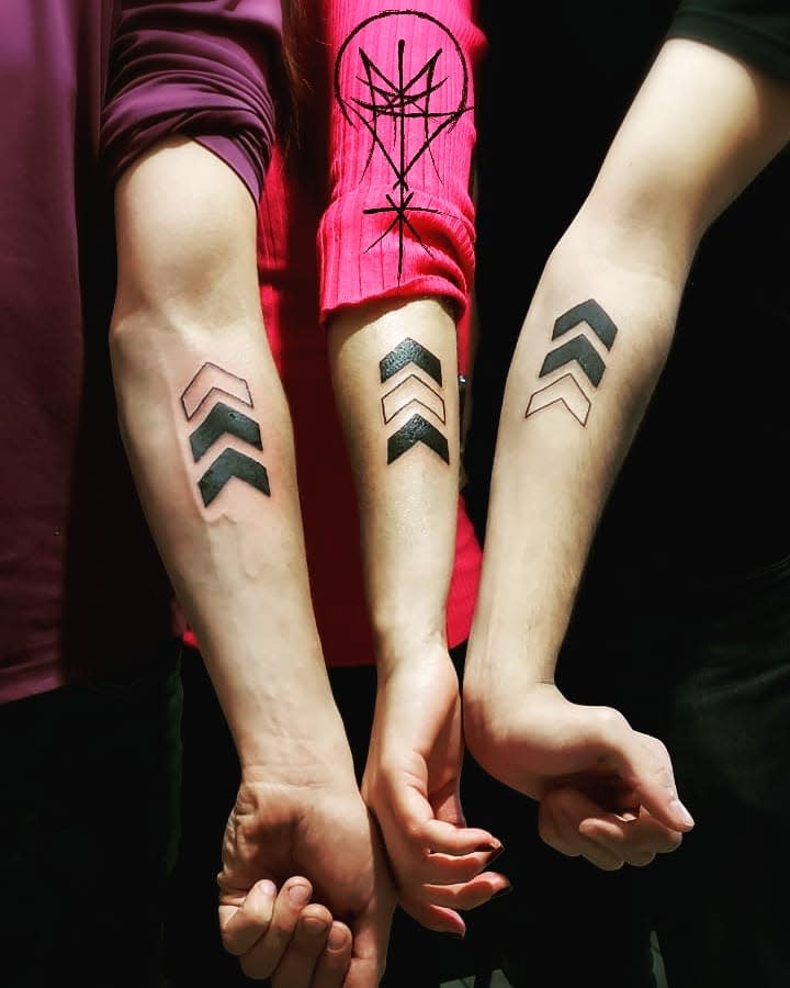 Four arms with matching triangle sequence tattoos, varying from hollow to filled